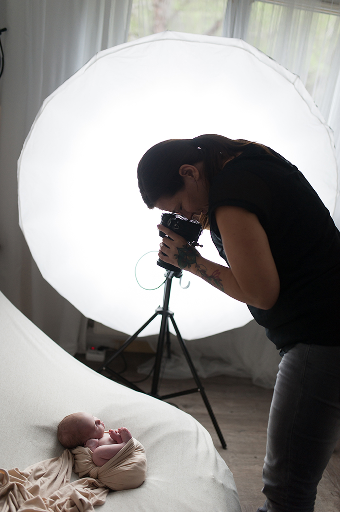 Photographe en pleine séance avec un nouveau-né.