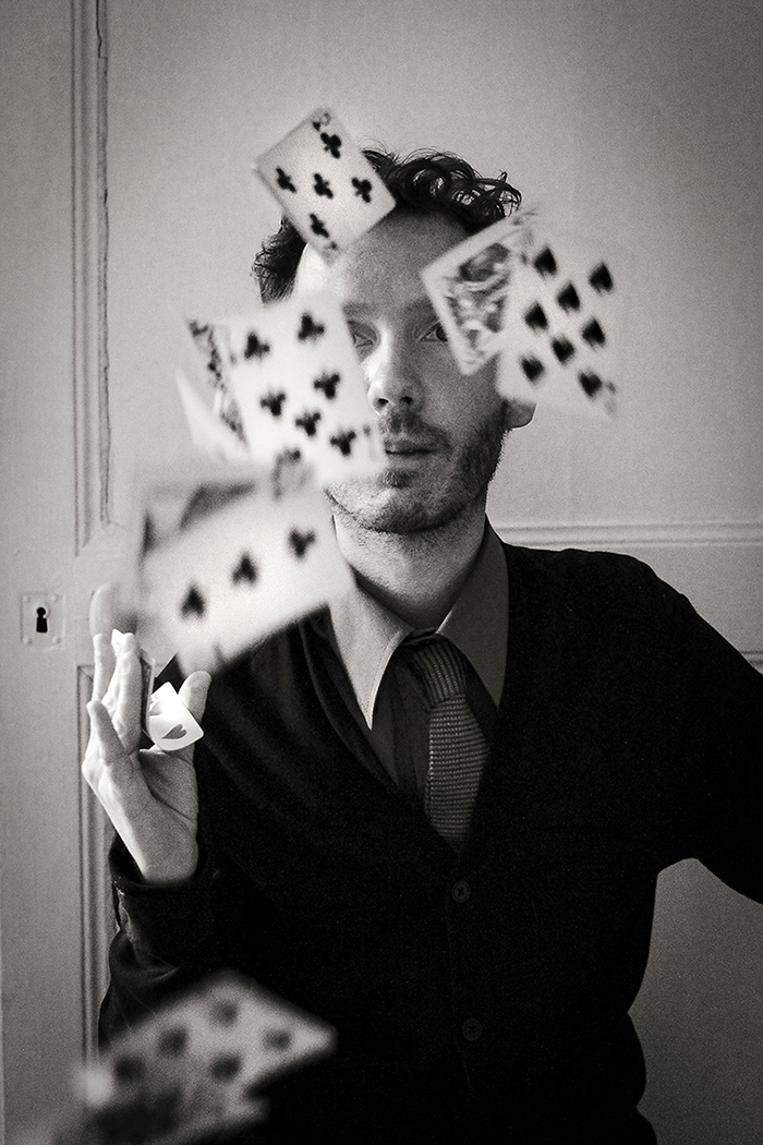 Photographie argentique, un homme, peut-être un magicien, qui joue avec des cartes.