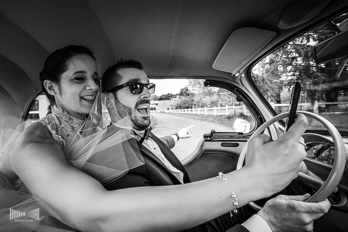 Photographie noir et blanc de mariés dans une voiture