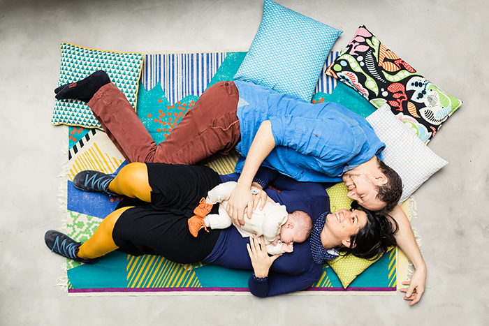 Photo d'une famille allongés sur le canapé avec leur petit bébé dans les bras. Une image tendre de Caroline Vidal.