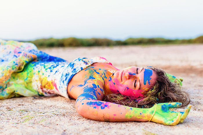 Un portrait colorée d'une jeune femme allongée sur le sol après avoir joué avec de la peinture !