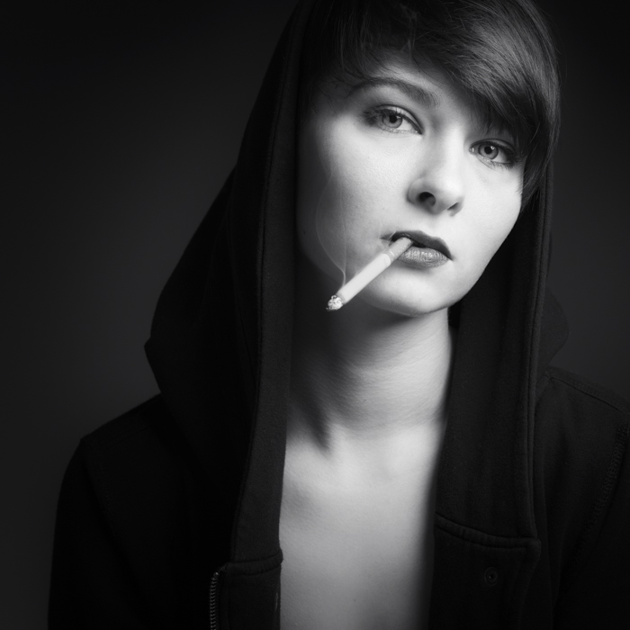 Portrait de femme en noir et blanc, elle a une cigarette à la bouche. Portrait artistique fine-art.