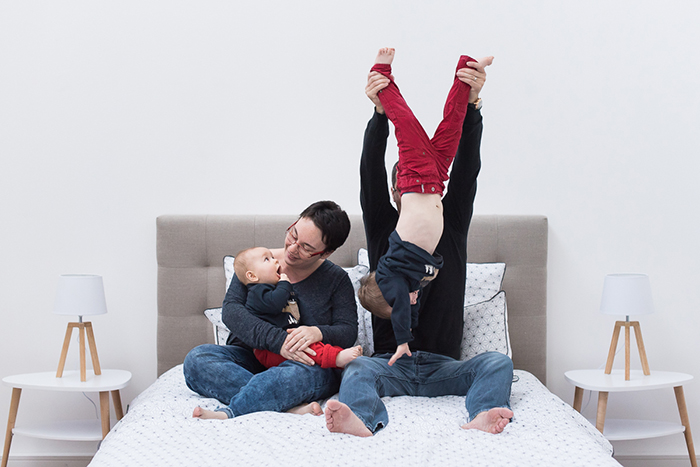 Séance photo de famille en studio lifestyle. Un espace aménagé pour reproduire une chambre neutre et photographier les clients dans une scène de vie.