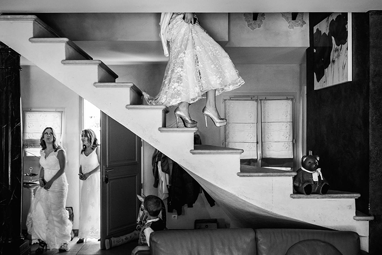 Photo de mariage en noir et blanc : la mariée descend les escaliers.