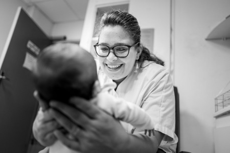 Une infirmière soigne un bébé et lui sourit.